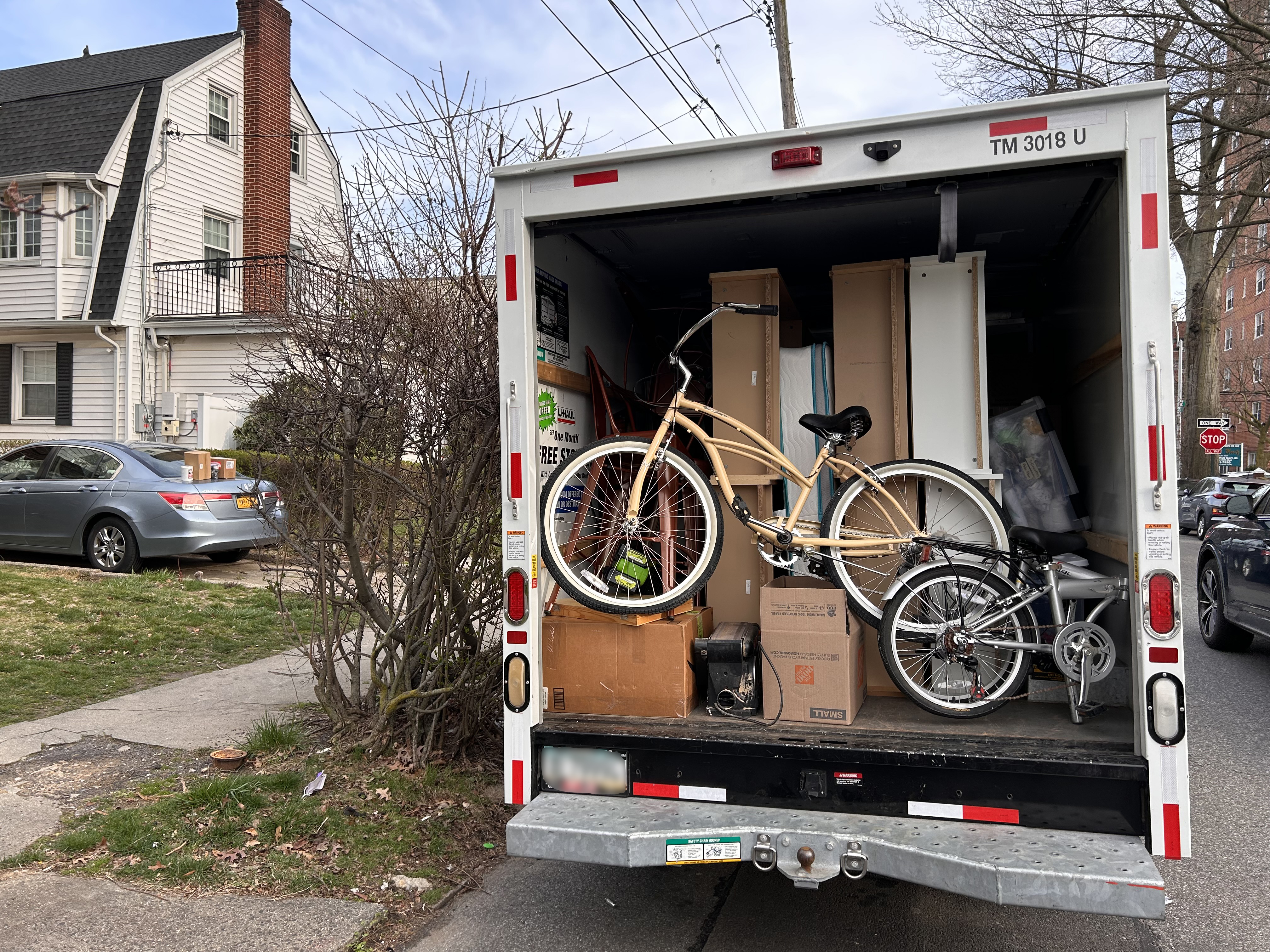 A picture of a moving van with a bike in front of a home in Queens.