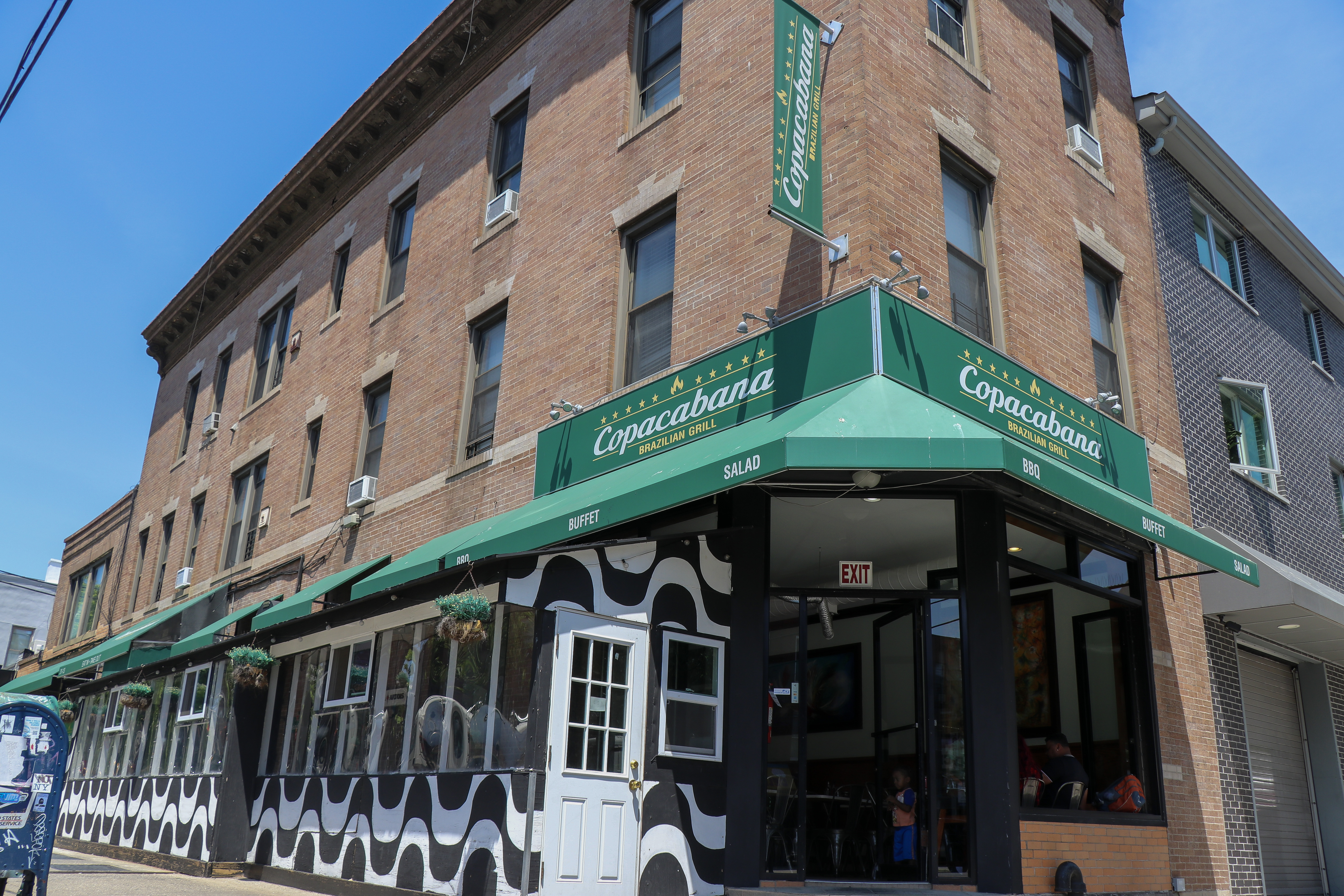 A restaurant on a corner with a green awning.