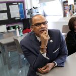 Schools Chancellor David Banks sits at a classroom desk.