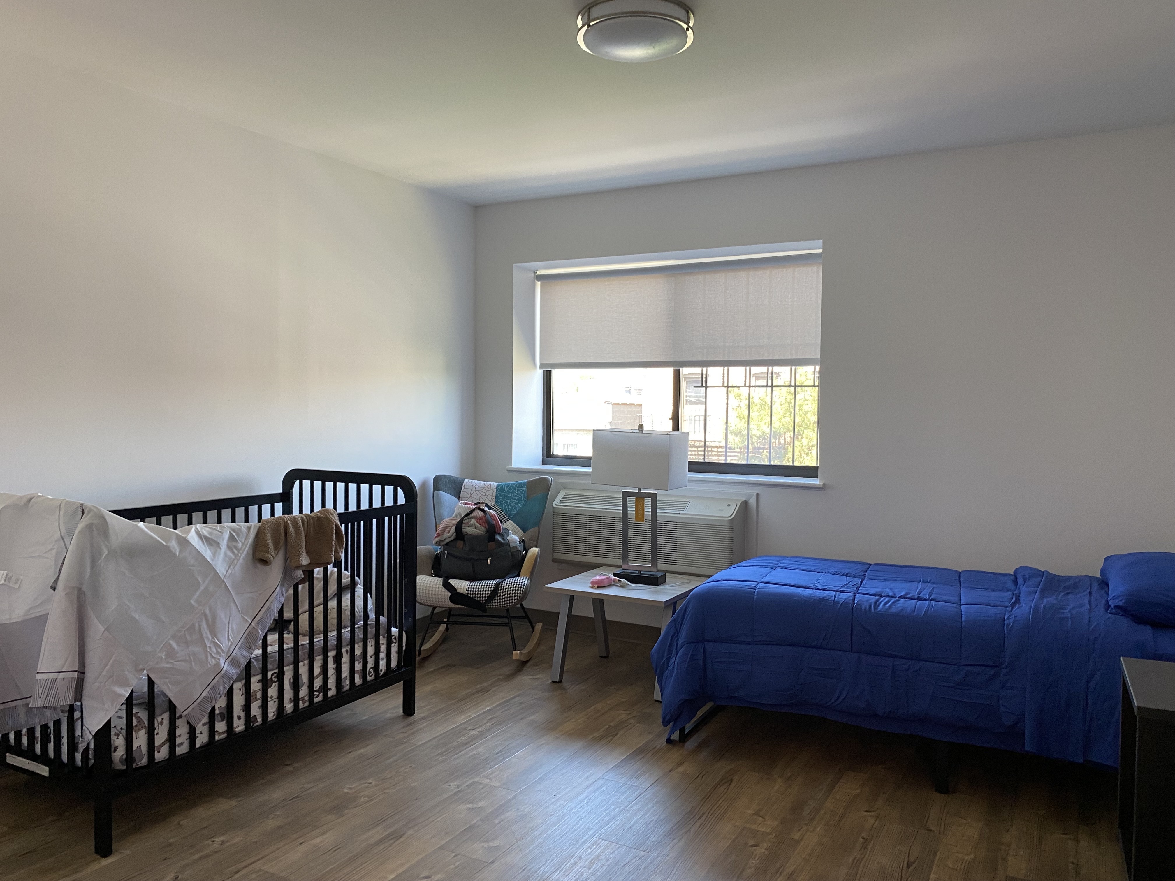 A room in one of the New York Foundling's Bronx buildings, where a crib is pressed up against one wall and a twin bed alongside another.